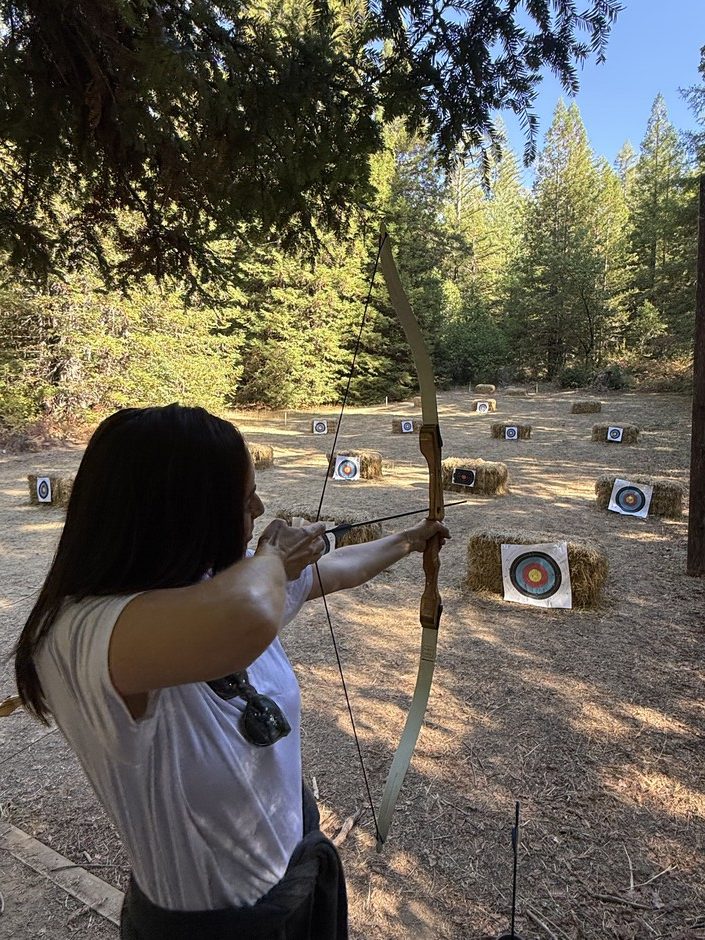 Attendee drawing a longbow on the Camp Navarro archery range